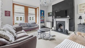 A modern living room with a fireplace, a sofa, a coffee table, and a television. - Spacious 4 Bedroom Townhouse Close to City Centre, Barbican, Hoe & Moors (Plymouth)