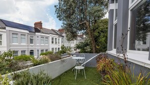 A courtyard with artificial grass, a white metal table and chair, and a large tree. - Spacious 4 Bedroom Townhouse Close to City Centre, Barbican, Hoe & Moors (Plymouth)