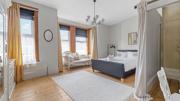 A bedroom with a large bed, a dresser, a chair, and a window with curtains. - Spacious 4 Bedroom Townhouse Close to City Centre, Barbican, Hoe & Moors (Plymouth)