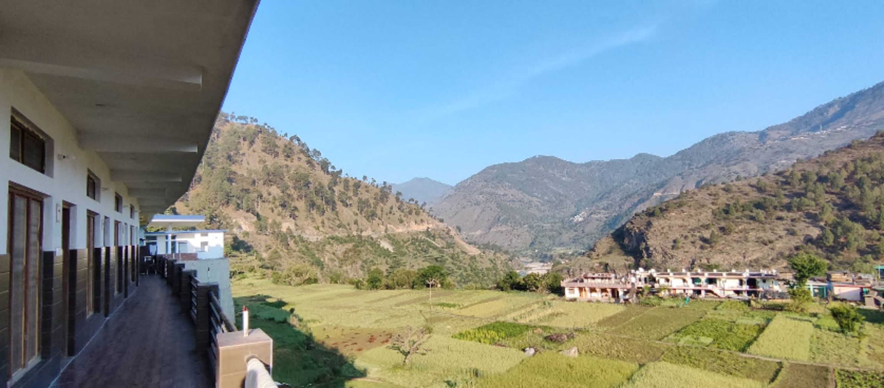 A view of a building with a balcony overlooking terraced fields and mountains.