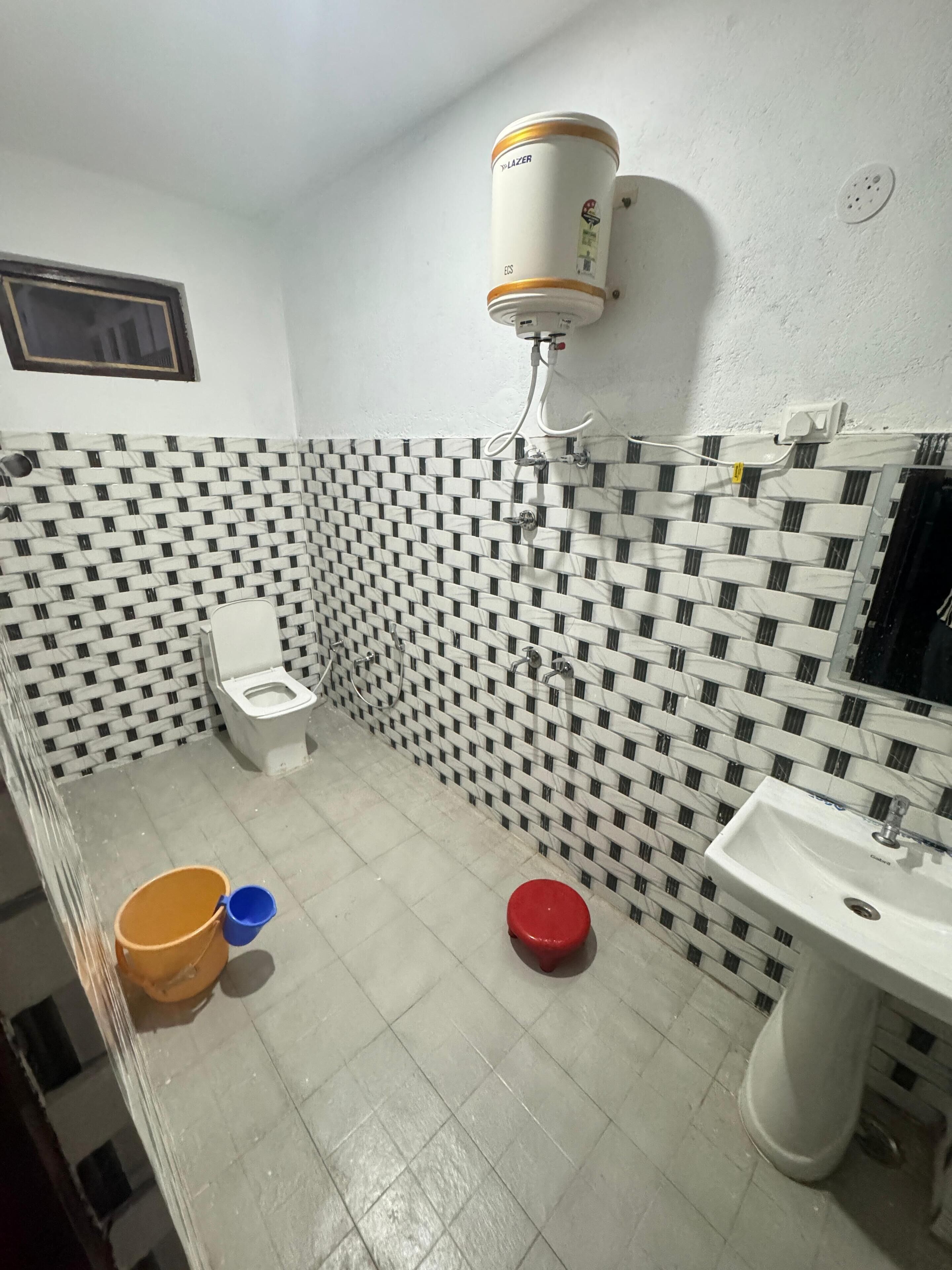 Une salle de bain comprenant des toilettes, un lavabo, un radiateur fixé au mur et un sol carrelé.