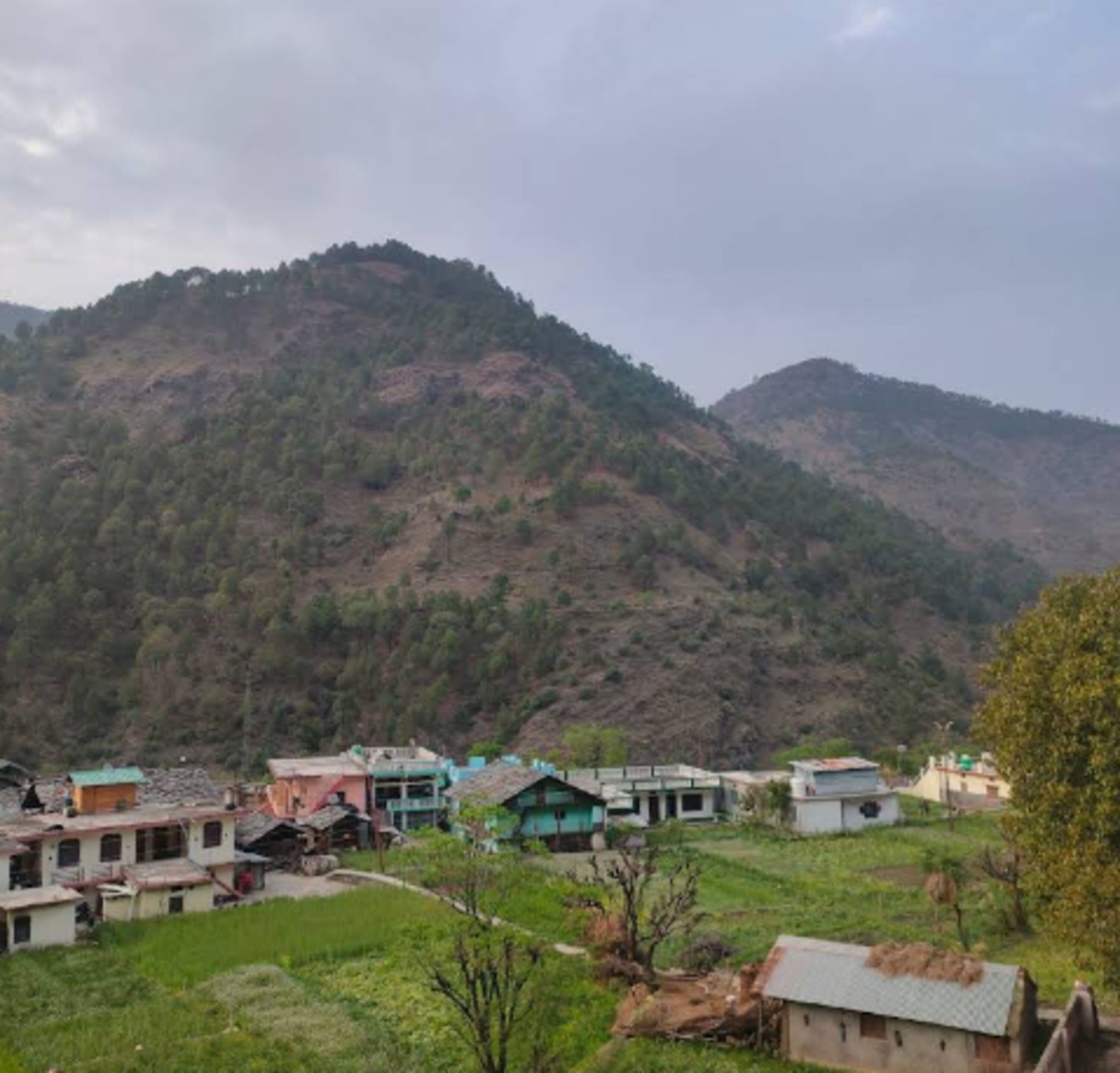 A village with houses on a hillside, surrounded by mountains.