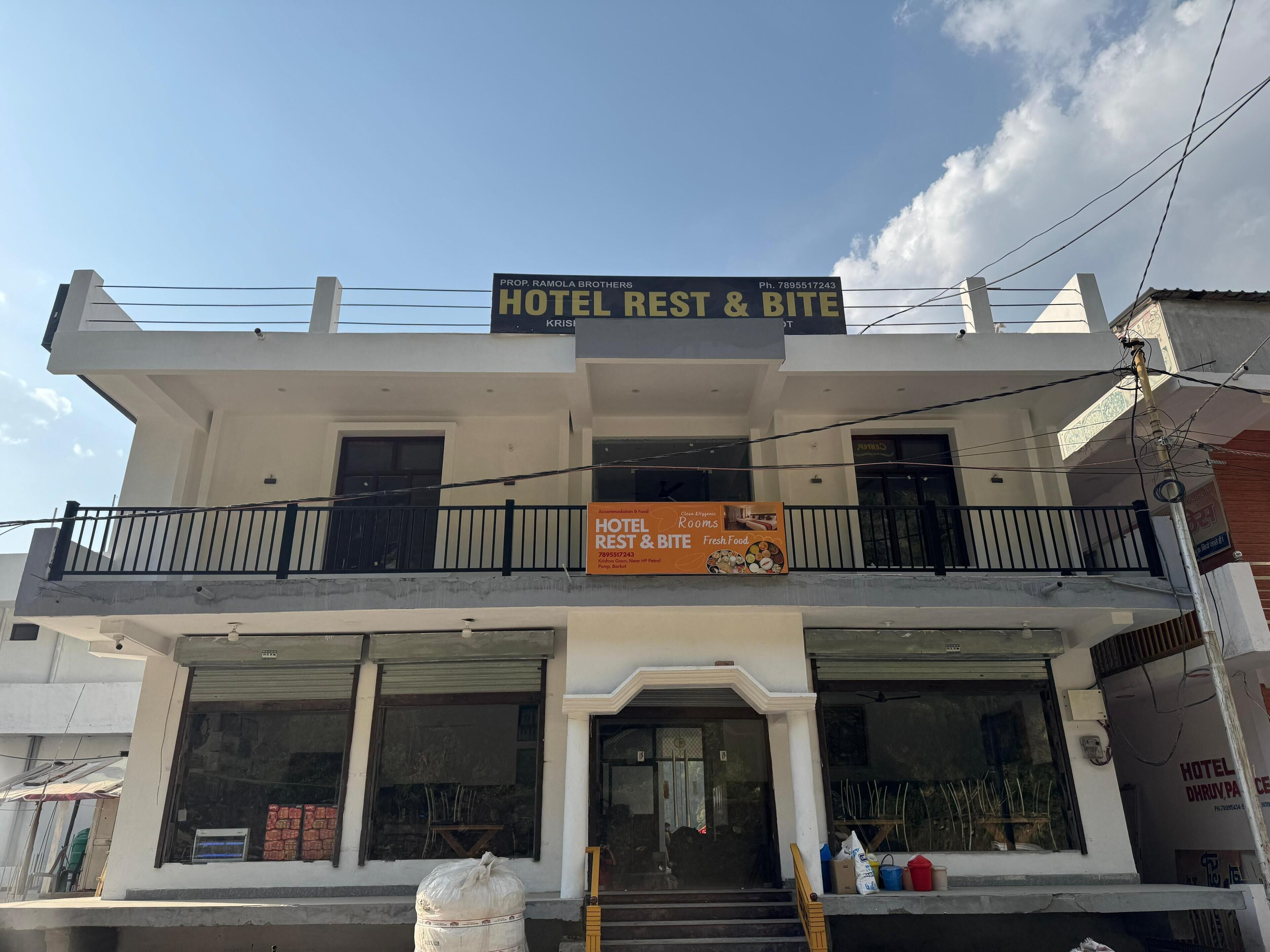 A two-story building with a sign for 'Hotel Rest & Bite' and a balcony with railings.