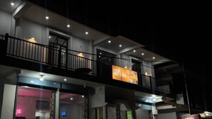 A two-story building with balconies, a neon sign, and a sign advertising a hotel, restaurant, and bar. - Hotel Rest and Bite (Rajgarhi)