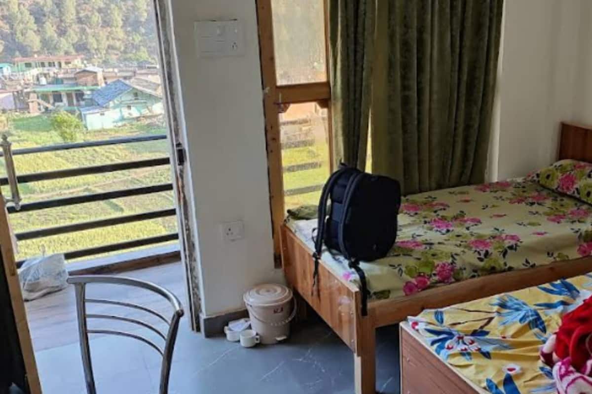 A bedroom with a bed, a suitcase, and a view of a green landscape through a window.
