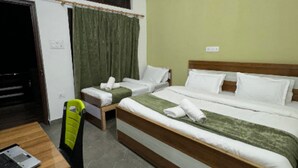 A hotel room with a large bed, two smaller beds, a desk, and a chair. - Hotel Rest and Bite (Rajgarhi)