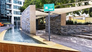 A modern building with a stone facade, a water feature, and an assembly point sign. - Stylish 1BR Dubai Marina w Pool and Gym (Dubai)