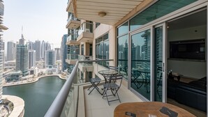 A balcony with a glass railing overlooking a marina and city skyline. - Stylish 1BR Dubai Marina w Pool and Gym (Dubai)