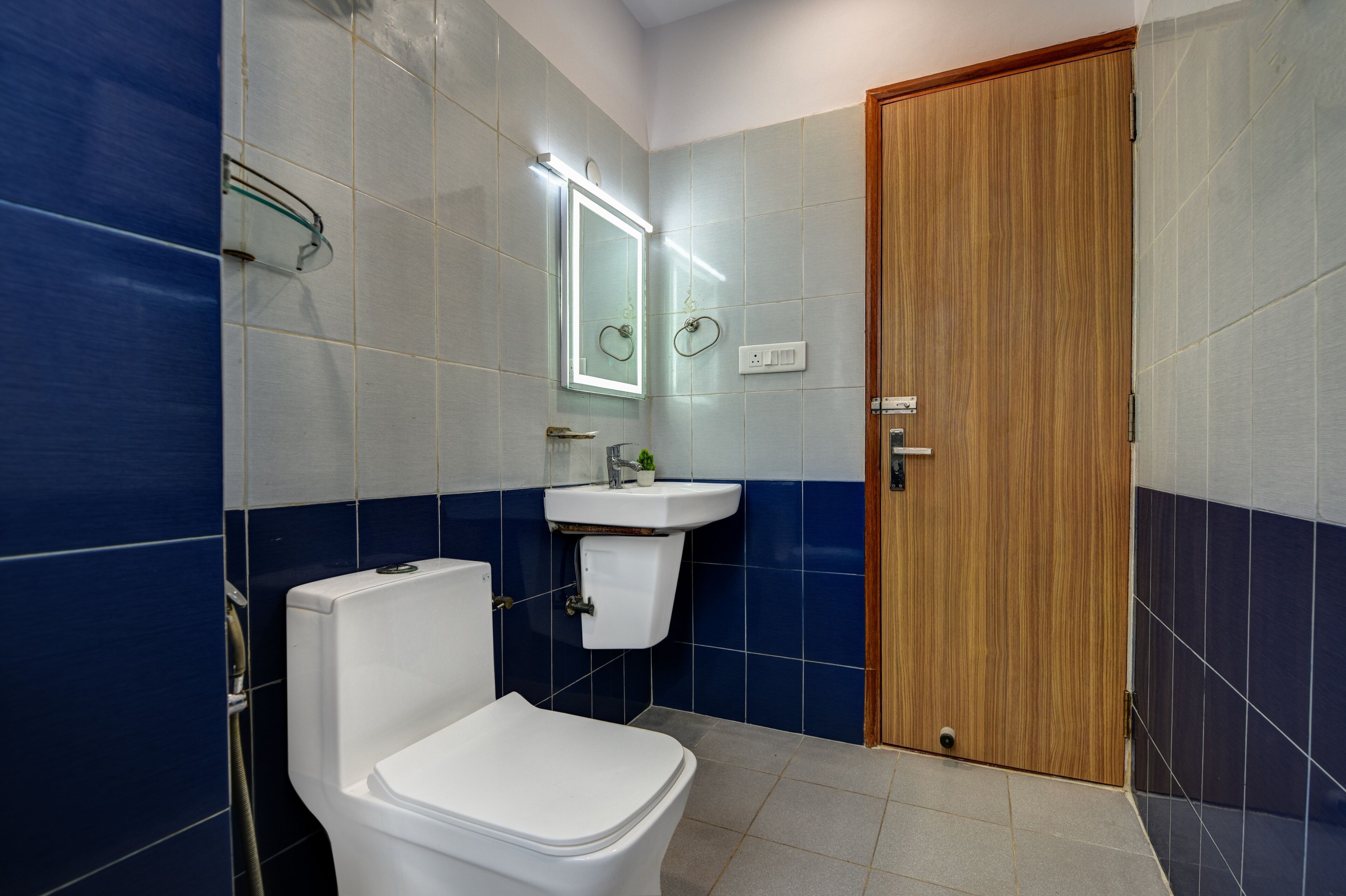 A bathroom with a toilet, sink, mirror, and wooden door.