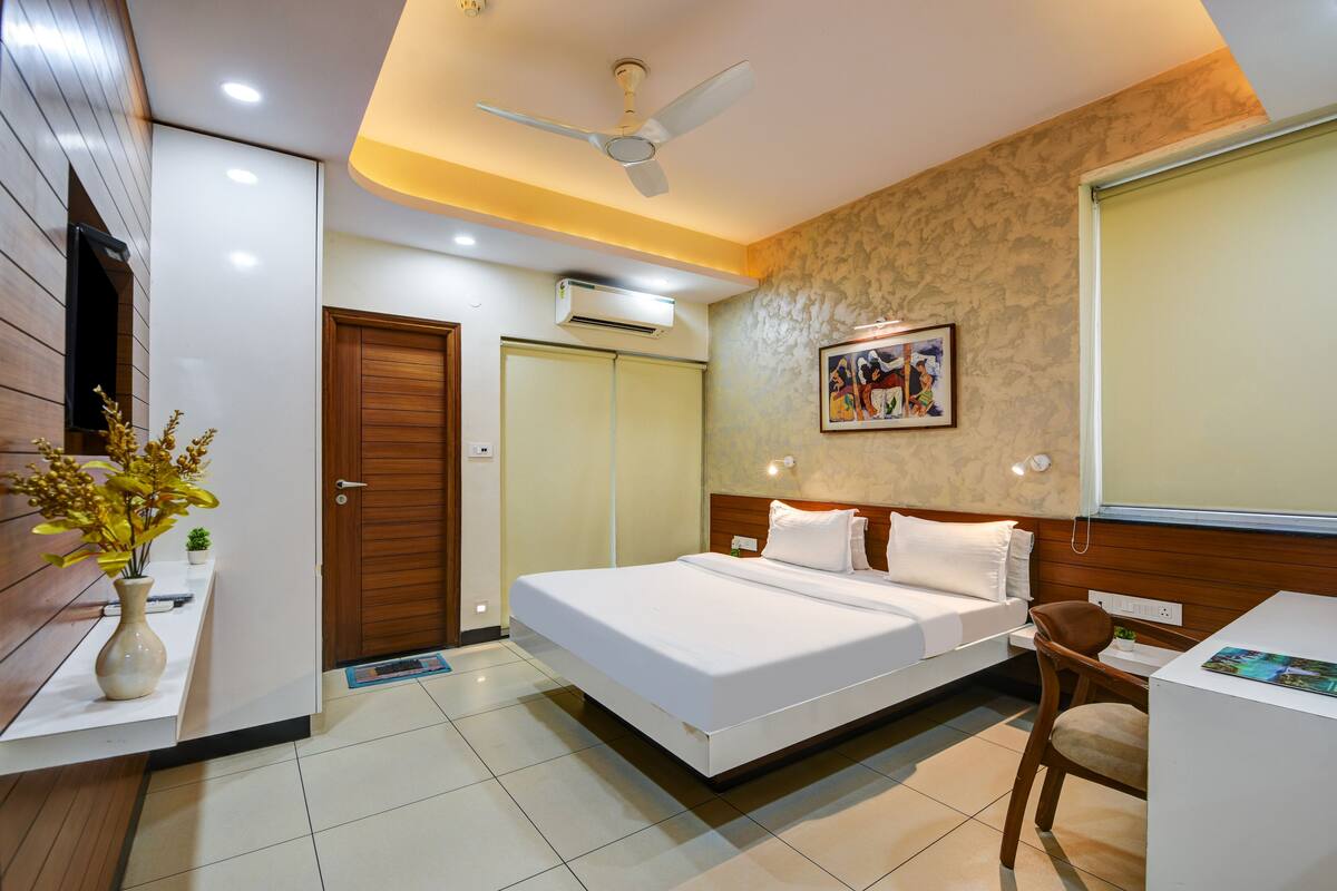 A hotel room with a bed, desk, chair, and a ceiling fan.