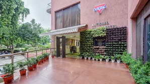 Un hostal National con fachada roja, un letrero y una pared de plantas en macetas.