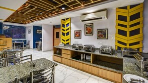 Un restaurante con mostrador central, varias mesas y sillas.