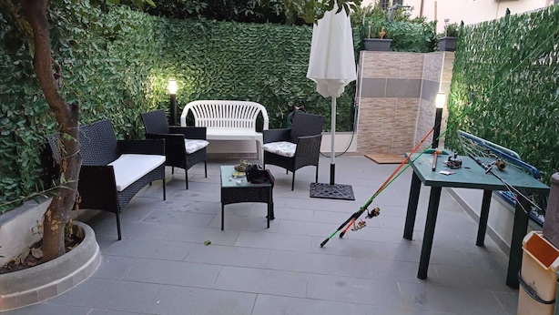 A patio area with outdoor furniture, a table with fishing rods, and a decorative wall.