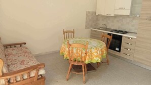 A compact kitchen with a dining table, chairs, and a sofa.