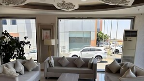 A modern living room with two sofas, a coffee table, and a large window with a view of a parking lot. - Osus G (Yanbu)