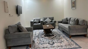 A modern living room with two grey sofas, a coffee table, and a patterned rug. - Osus G (Yanbu)