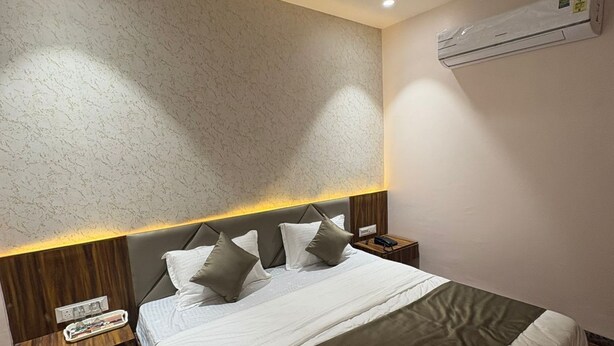 Una habitación de hotel moderna con una cama grande, cabecera de madera, mesitas de noche y un ventilador de techo.