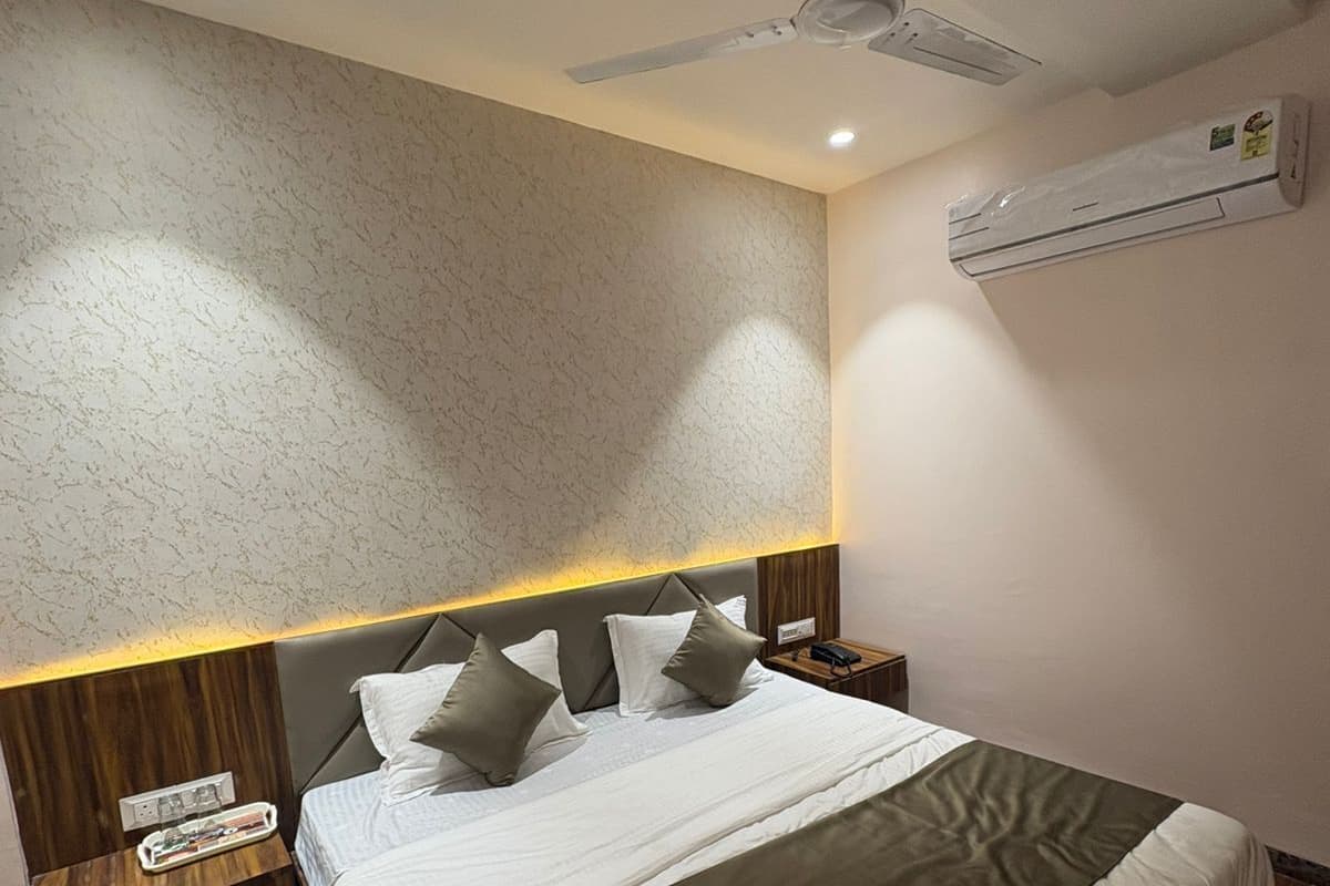 Een moderne hotelkamer met een groot bed, een houten hoofdeinde, nachtkastjes en een plafondventilator.