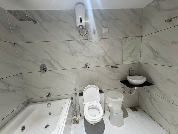 Een moderne badkamer met een bad, toilet en wastafel.
