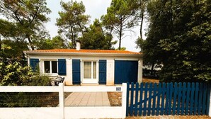 Une maison avec un toit rouge, des volets bleus et une clôture blanche.