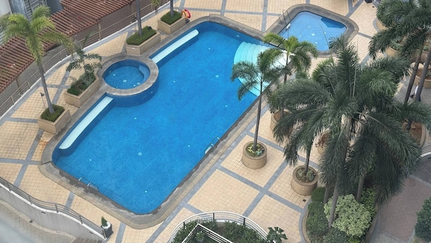 Une piscine sur le toit, divisée en plusieurs zones, entourée de palmiers et agrémentée d’espaces de détente en plein air.