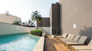 Un espace piscine avec des chaises longues et un palmier.
