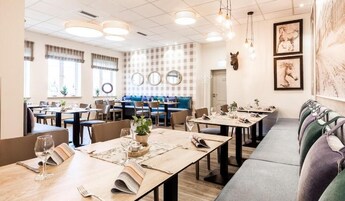 Ein Restaurant mit mehreren Tischen und Sitzecken, manche mit Pflanzen und Speisekarten.