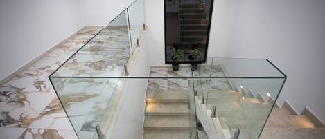 Een moderne trap met glazen balustrades en een marmeren vloer.
