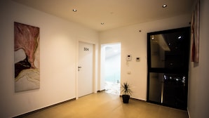 A hallway with a door labeled "304", a potted plant, and a painting on the wall. - Villa Klaus Center Hotel  (Tirana)