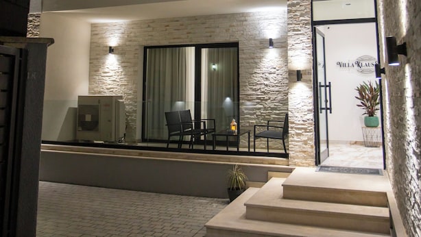 A modern two-story building with a balcony, a staircase leading to the entrance, and a potted plant near the door. - Villa Klaus Center Hotel  (Tirana)