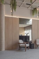 Un interior moderno con paneles de madera, plantas colgantes y dos sillones tapizados.
