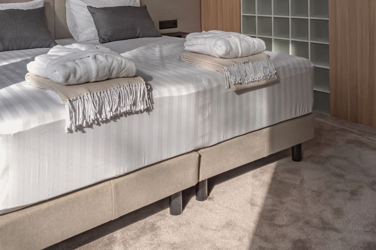 A modern bedroom with a large bed, a nightstand, and a wall-mounted light.