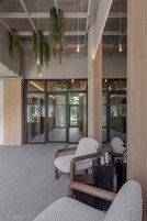 Un interior moderno con asientos, plantas colgantes y luz natural.