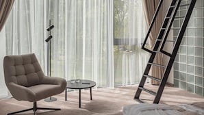 Un dormitorio moderno con una ventana grande, una silla, una cama y una escalera.