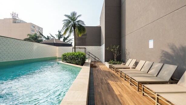 Una piscina con sillas de descanso y una palmera.