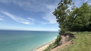 A coastal landscape with a grassy area, a cliff, and a beach. - Five bedroom home overlooking Lake MI, North of Leland. (Leland)