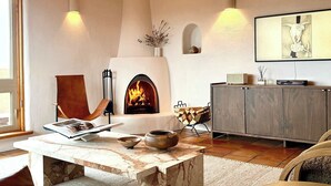 A cozy living room with a fireplace, a comfortable chair, a coffee table, and a modern cabinet.