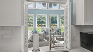 A kitchen with a view of a garden through large windows.