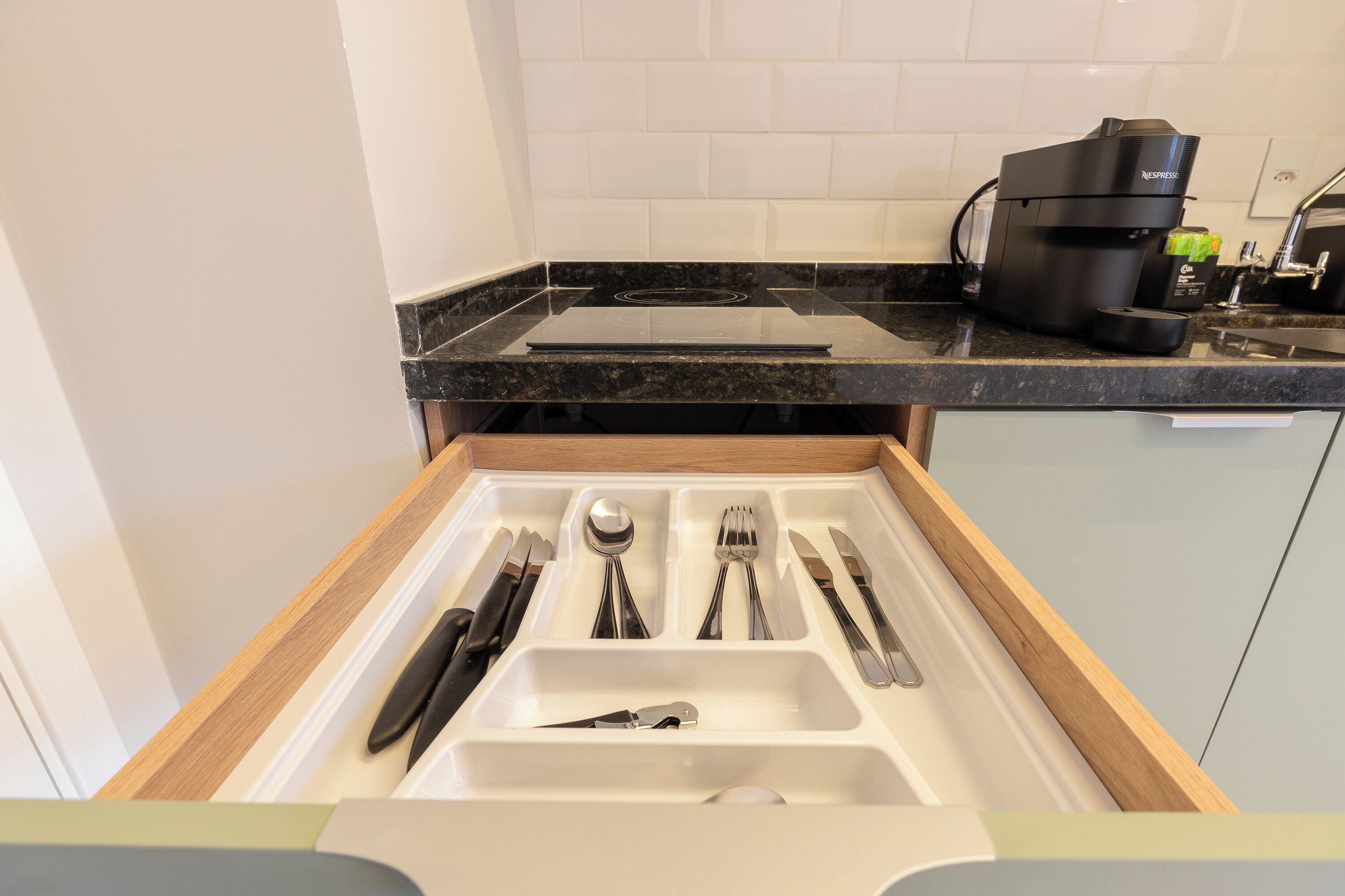 A kitchen drawer with utensils and a coffee machine.