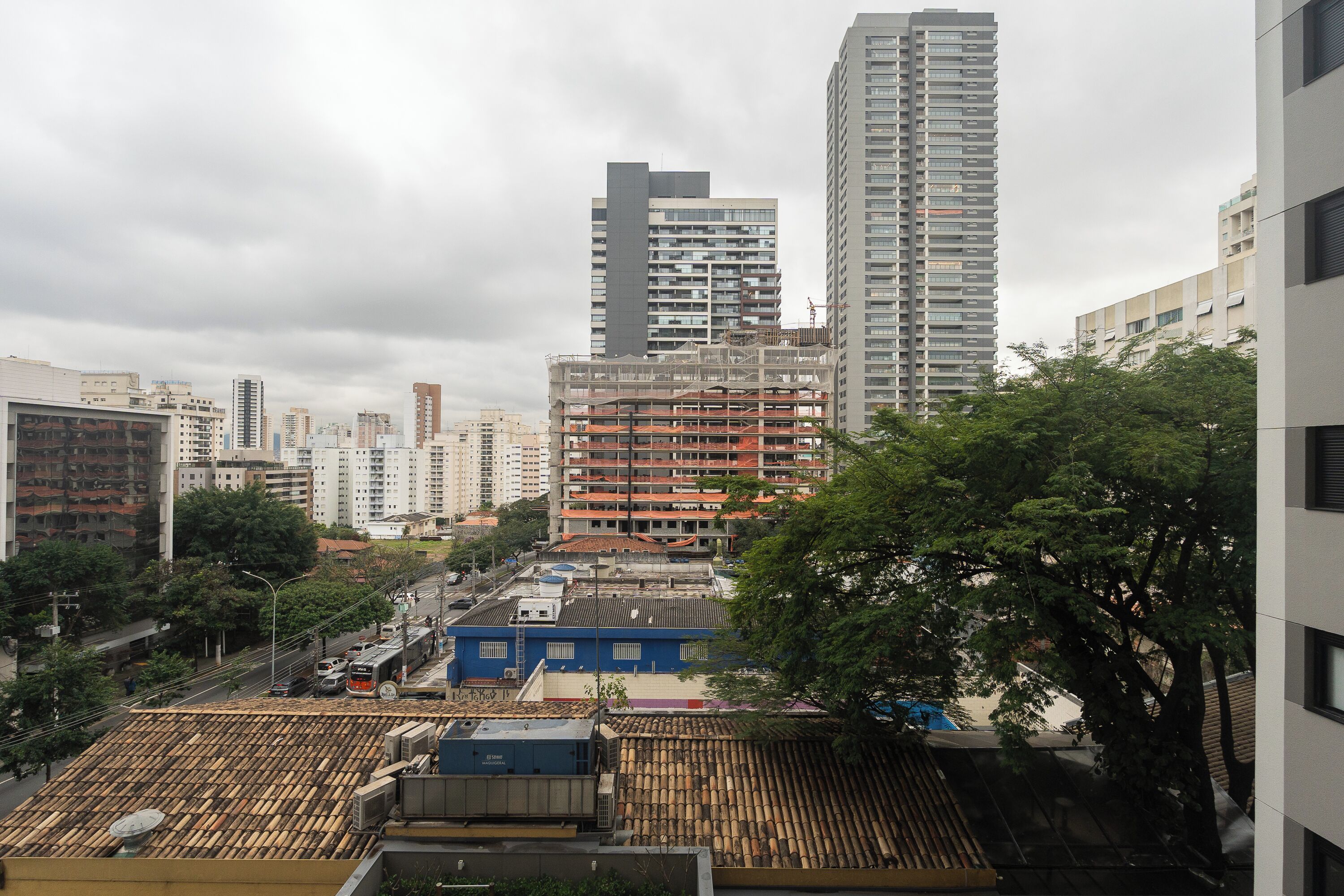 Un paysage urbain avec des immeubles modernes de grande hauteur, un chantier de construction et des toits traditionnels recouverts de tuiles.