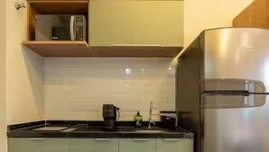 Eine Küche mit einem Edelstahl-Kühlschrank, einer Mikrowelle und einer Kaffeemaschine auf der Arbeitsfläche.