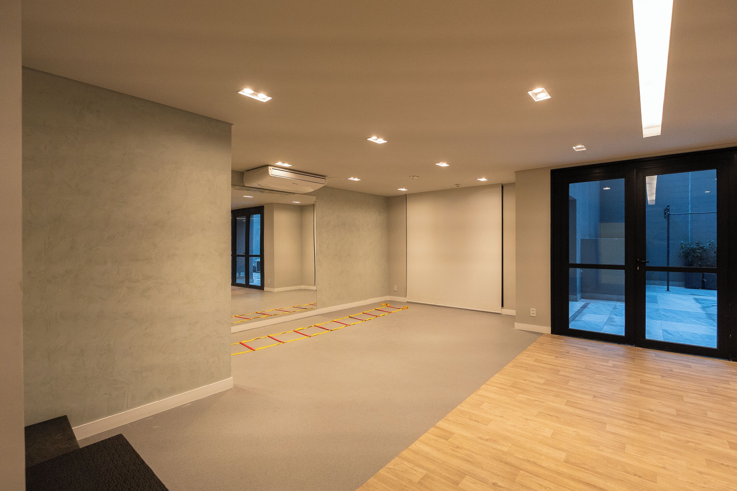A spacious room with a large sliding glass door, recessed ceiling lights, and a visible air conditioning unit.
