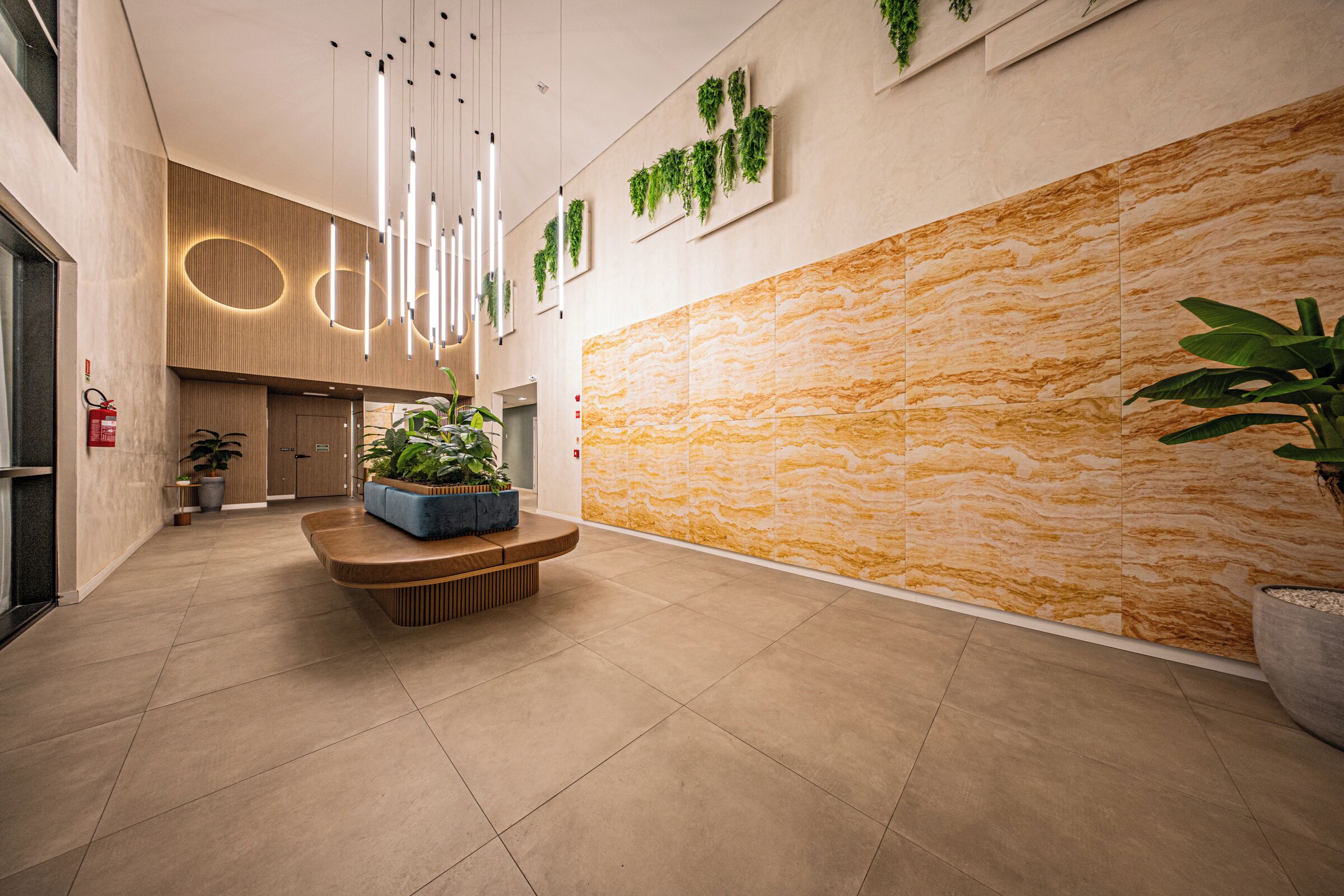 A modern lobby with a marble wall, a wooden bench, and hanging plants.