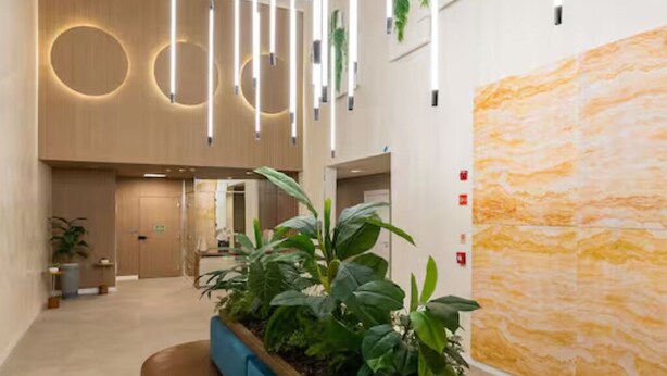 Eine moderne Lobby mit einer zentralen Pflanzung, Holzvertäfelung und einer großen, strukturierten Wand.