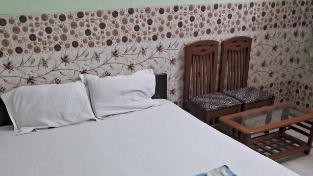 Ein Schlafzimmer mit einem großen Bett, zwei Holzstühlen und einem kleinen Tisch.