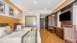A hotel room with two beds, wooden flooring, a TV mounted on the wall, and a large mirror. - Voyage Alpine Abode (Gangtok)