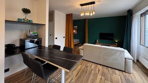 A modern living space with a dining area, a sofa, a TV, and a plant. - Lugano Lakeside: The Nest - your refuge in Castagnola (Lugano)