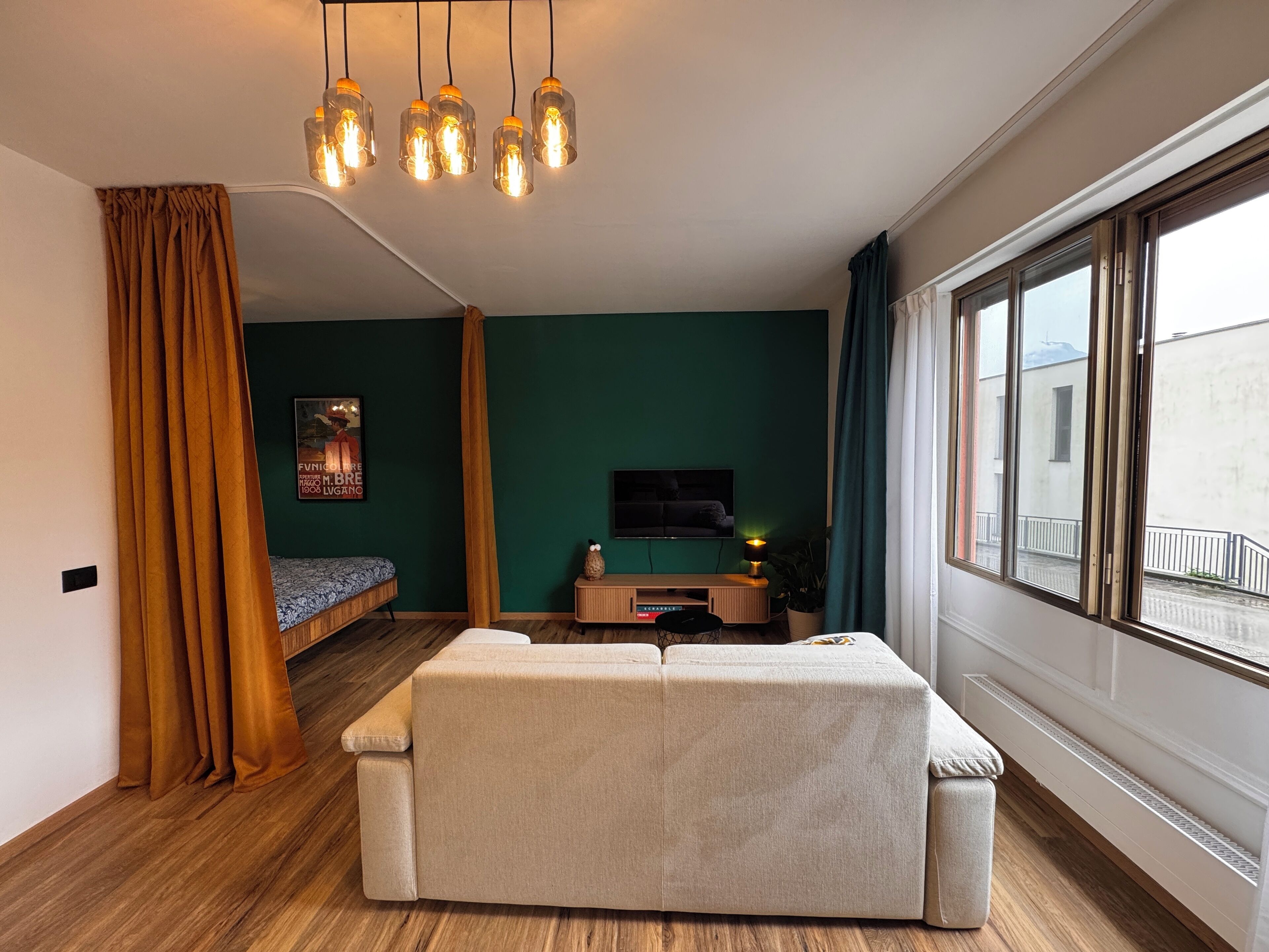A modern living room with a sofa, a TV, a small table, and a window with curtains.