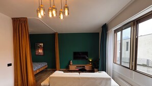 A modern living room with a sofa, a TV, a small table, and a window with curtains. - Lugano Lakeside: The Nest - your refuge in Castagnola (Lugano)