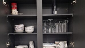 Une cuisine équipée d’un four à micro-ondes, d’un grille-pain et d’étagères contenant des bols, des assiettes et des verres.